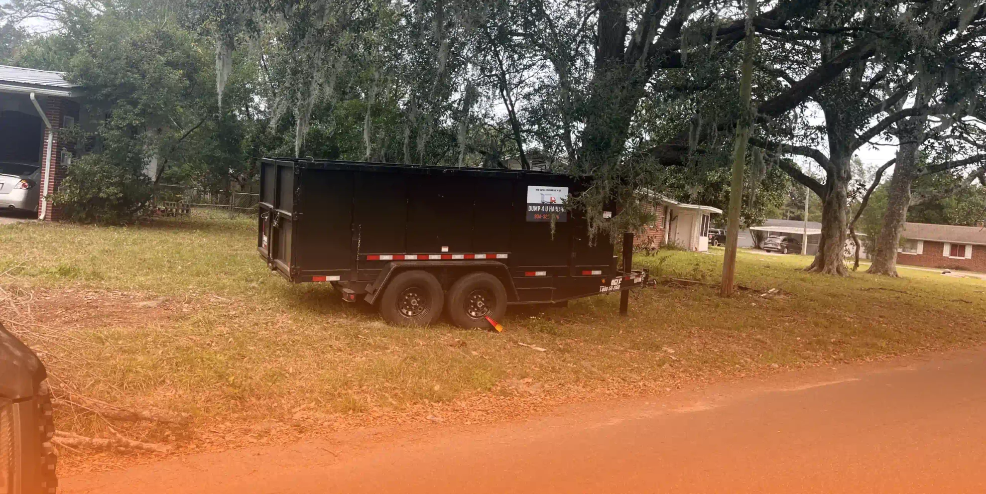 black big dumpster outside of a house on patio with grass and trees around